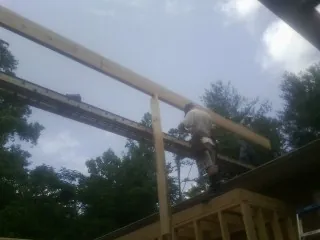 Carpenter setting a ridge beam over a new addition frame — Ice Dam Removal by Roofing Brothers in Bardolph
