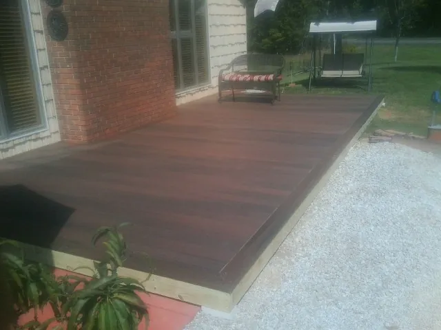 Freshly stained wood deck built against a brick home in Bardolph