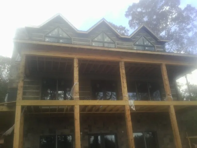 Dormers and porch framing on a large log home under construction — Roof Coating work by our crew in Bardolph