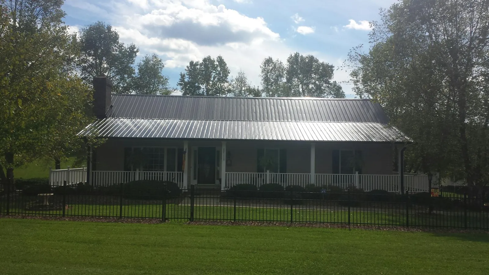 Gray metal roof on a brick ranch with a full width front porch — Gutter Guard Installation work by our crew in Bardolph